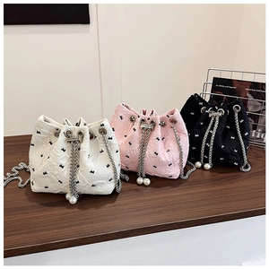 Detailed view of textured bucket bags with bow embroidery and pearl chain tassels