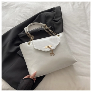White leather tote bag with deer charm and gold chain detail on a black blazer