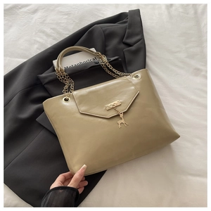 Detail of khaki tote bag featuring gold chain handle and lucky deer metal charm