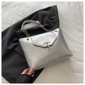 Detail of silver metallic tote bag with gold chain strap and deer pendant on black blazer