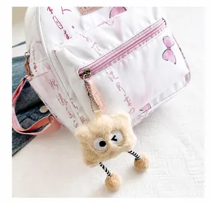 Gros plan du mini sac à dos blanc avec papillons et porte-clés monstre en peluche