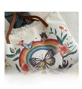 Gros plan sur un sac en toile blanc avec imprimé floral artistique et bordures effilochées