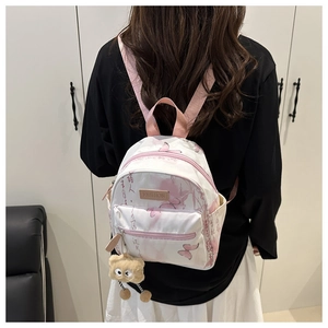 Détail du mini sac à dos blanc avec imprimés papillons roses et breloque peluche