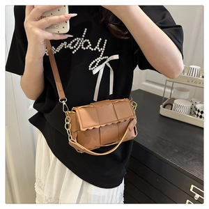 Gros plan d'un sac bandoulière marron en similicuir tressé avec bords festonnés stylés
