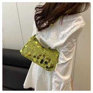 Détail du sac baguette à paillettes vert citron avec chaîne en argent sur l'épaule