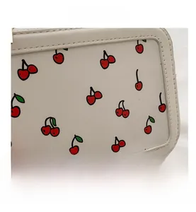 Detailed view of red cherry prints on white synthetic leather shoulder bag surface