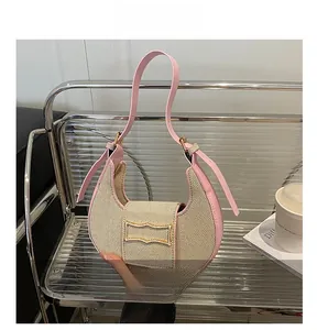 Detalle del ribete de cuero rosa y tela tejida beige en el bolso de media luna