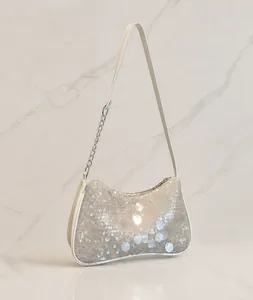 Detalle del bolso baguette de lentejuelas blancas con cadena de plata en una percha