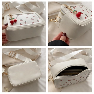 Vistas detalladas del bolso pequeño blanco con estampado de cerezas y colgante a juego