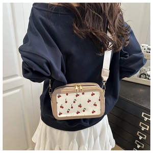 Detail of crossbody bag featuring cherry print, transparent window and wide woven strap