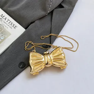 Detailed view of golden metal bow evening bag with elegant chain strap and glossy finish