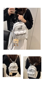 Détail d'un sac à dos blanc avec motifs papillon, calligraphie et pendentif en peluche