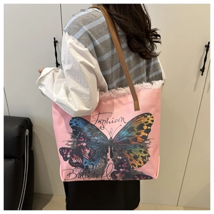 Detail of pink canvas tote with butterfly print and frayed fringe edge on a shoulder strap