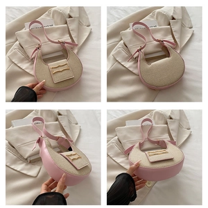 Detalle del bolso de media luna en tela beige con ribete de cuero rosa y hebilla dorada