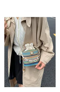 Close-up of bohemian woven straw bag with colorful stripes, pearl accents and chain strap