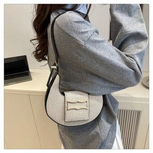 Detalle del bolso de hombro tipo media luna en tweed con ribete de cuero negro