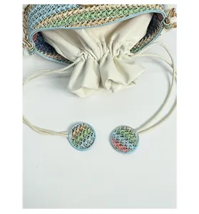 Close-up of woven straw bucket bag with white leather drawstring closure and chain strap