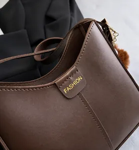Detail view of refined stitching and Fashion logo on a dark brown leather bucket bag