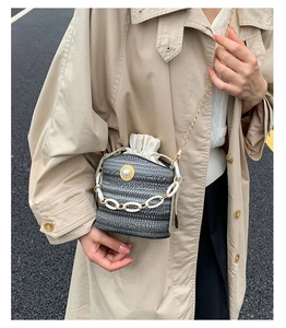 Detail of woven bucket bag with pearl accent, acrylic chain and gold chain strap