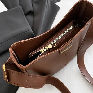Close-up of smooth gold metal zipper and brand logo on a brown PU leather bucket bag