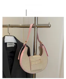Detalle de bolso medialuna tejido con ribete de cuero rosa y herrajes dorados