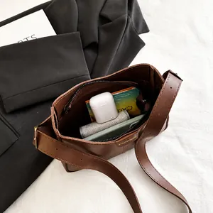 Internal view of brown retro shoulder bag showing space for phone and earphones