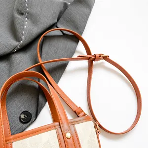 Detail des braunen Leder-Schultergurts mit Metallschnalle an der Monogramm-Tasche