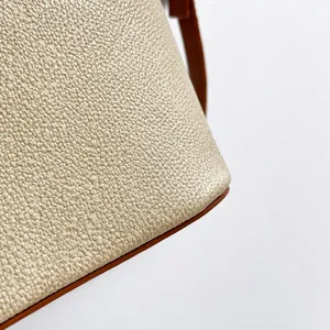 Detail der cremefarbenen Lederstruktur mit braunem Kantenschutz und Monogramm-Prägung