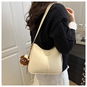 Detail of cream beige hobo bag with matte PU texture and brown plush monster charm