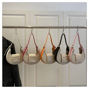 Detalle de cinco bolsos de lona en forma de luna con adornos de cuero de colores