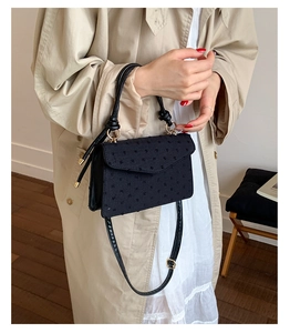 Détail d'un sac chic en jacquard noir texturé avec poignée ronde et bandoulière élégante