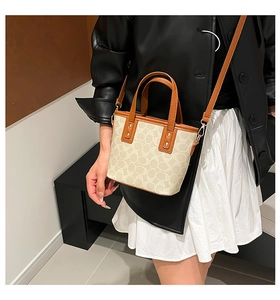 Detailansicht der cremefarbenen Monogramm-Canvas-Tasche mit braunen Ledergriffen