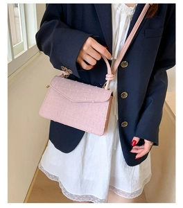 Petit sac bandoulière rose texturé porté avec un blazer marine et robe en dentelle