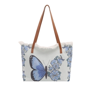 Blue butterfly canvas tote bag with brown leather handles and fringe trim detail