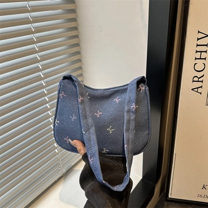 Blue denim underarm bag with colorful embroidered bows and dual handles for women