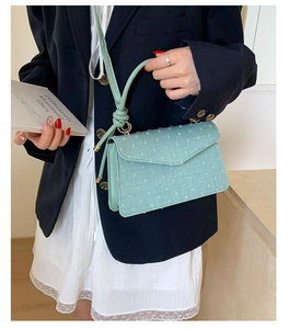 Détail du sac à bandoulière en tissu vert menthe avec sangle à nœud et rabat enveloppe