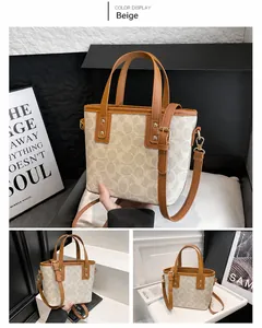 Detail der beigen Monogramm-Beuteltasche mit braunem Lederbesatz und Goldmetall-Details
