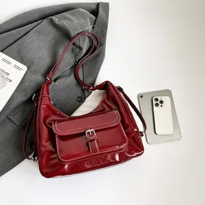 Detail view of burgundy patent leather hobo bag with buckled pocket and strap