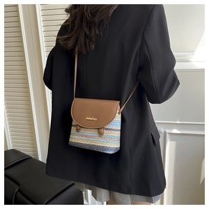 Petit sac bandoulière tissé arc-en-ciel porté sur un blazer noir style élégant