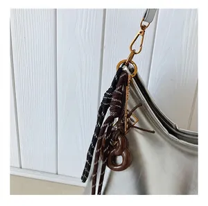 Detalle del bolso plateado con gancho de metal dorado y detalles de cuerdas tejidas