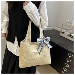 Detalle de un bolso tote de paja tejida beige con un pañuelo estampado de estilo francés