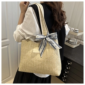 Detalle de bolso tote de paja trenzada con pañuelo de seda y correas para el hombro
