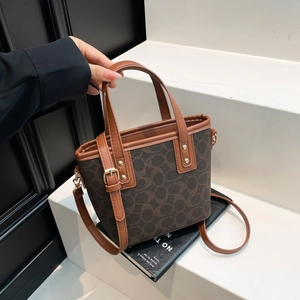 Retro Monogramm Eimertasche mit braunen Ledergriffen und Goldnieten auf Treppe