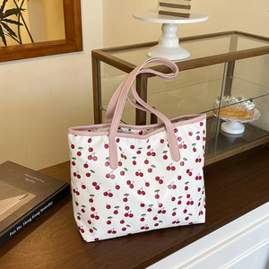 Sac fourre-tout blanc à imprimé cerises et anses roses dans un décor de café
