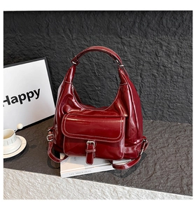 Detail of dark red faux leather tote bag featuring white contrast stitching and front pocket