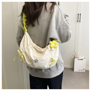 Detalle de bolso bandolera de nailon blanco con cordón amarillo y colgante de flor en modelo