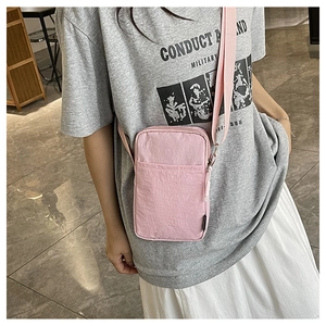 Detail of pink nylon mini crossbody phone bag with front pocket and adjustable strap