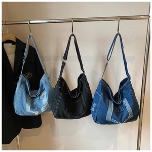 Drie vintage denim draagtassen in blauwe en zwarte kleuren hangend aan metalen haken