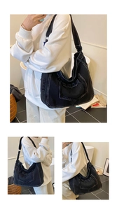 Detail van zwarte denim draagtas met witte contrasterende stiksels en gerafelde randen