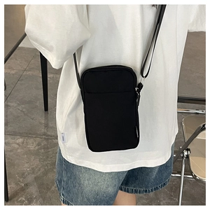 Close-up of black fabric mini crossbody bag worn by model over white t-shirt